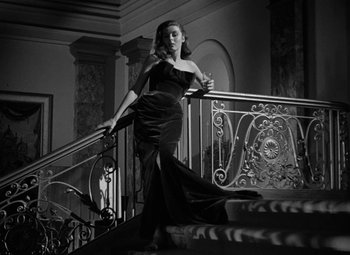 Movie still from “The Bad and the Beautiful” (1952), directed by Vincente Minnelli – A woman in a black dress standing on a staircase; Medium shot, Low angle