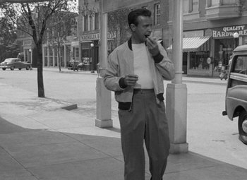 Movie still from “The Bad and the Beautiful” (1952), directed by Vincente Minnelli – A man standing on the side of the street smoking a cigarette; Wide shot, Low angle