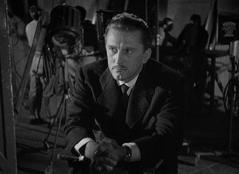 Movie still from “The Bad and the Beautiful” (1952), directed by Vincente Minnelli – A man in a suit and tie holding a cane; Close Up shot, Over the shoulder angle