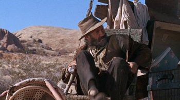 Movie still from “The Ballad of Cable Hogue” (1970), directed by Sam Peckinpah – A man sitting on top of a wooden pole; Wide shot, Low angle