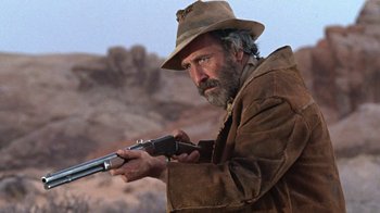 Movie still from “The Ballad of Cable Hogue” (1970), directed by Sam Peckinpah – A man with a hat on holding a gun; Close Up shot, Low angle