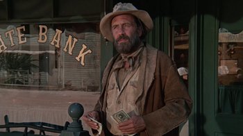 Movie still from “The Ballad of Cable Hogue” (1970), directed by Sam Peckinpah – A man in a cowboy hat holding money in his hands; Medium shot, Low angle