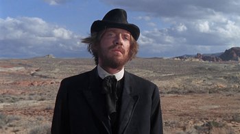 Movie still from “The Ballad of Cable Hogue” (1970), directed by Sam Peckinpah – A man wearing a black suit and a black hat; Close Up shot, Low angle
