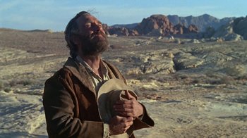 Movie still from “The Ballad of Cable Hogue” (1970), directed by Sam Peckinpah – A man with a beard is holding his hands in prayer; Medium shot, Low angle