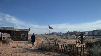 Movie still from “The Ballad of Cable Hogue” (1970), directed by Sam Peckinpah – A person standing in a field near a flag; Extreme Wide shot, Low angle