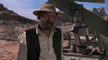 Movie still from “The Ballad of Cable Hogue” (1970), directed by Sam Peckinpah – A man with a beard and a hat is standing in a field; Medium shot, Low angle