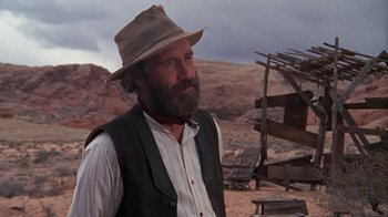 Movie still from “The Ballad of Cable Hogue” (1970), directed by Sam Peckinpah – A man with a beard wearing a hat and a vest; Medium shot, Over the shoulder angle