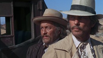 Movie still from “The Ballad of Cable Hogue” (1970), directed by Sam Peckinpah – Two men in hats and suits standing next to each other; Close Up shot, Low angle