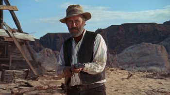 Movie still from “The Ballad of Cable Hogue” (1970), directed by Sam Peckinpah – A man in a hat holding a gun in the desert; Medium shot, Low angle