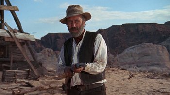 Movie still from “The Ballad of Cable Hogue” (1970), directed by Sam Peckinpah – A man in a hat and vest holding a gun in the desert; Medium shot, Low angle