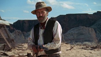 Movie still from “The Ballad of Cable Hogue” (1970), directed by Sam Peckinpah – An older man with a hat holding a gun in his hands; Medium shot, Low angle