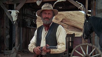 Movie still from “The Ballad of Cable Hogue” (1970), directed by Sam Peckinpah – An old man holding a gun while wearing a hat; Medium shot, Low angle