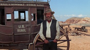 Movie still from “The Ballad of Cable Hogue” (1970), directed by Sam Peckinpah – A man standing in front of an old mail wagon; Wide shot, Low angle