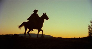 Movie still from “The Ballad of Gregorio Cortez” (1982), directed by Robert M. Young – A man riding a horse in a field at sunset; Wide shot, Low angle
