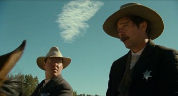 Movie still from “The Ballad of Gregorio Cortez” (1982), directed by Robert M. Young – Two men in hats and suits are looking at the sky; Medium shot, Low angle