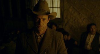 Movie still from “The Ballad of Gregorio Cortez” (1982), directed by Robert M. Young – A man wearing a cowboy hat in a dimly - lit room; Medium shot, Low angle