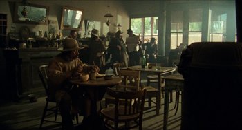 Movie still from “The Ballad of Gregorio Cortez” (1982), directed by Robert M. Young – A group of people sitting at tables in a room; Wide shot, Low angle