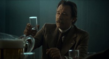 Movie still from “The Ballad of Gregorio Cortez” (1982), directed by Robert M. Young – A man in a suit and tie holding a glass of water; Close Up shot, Low angle