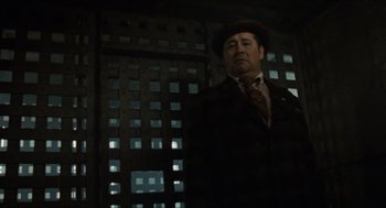 Movie still from “The Ballad of Gregorio Cortez” (1982), directed by Robert M. Young – A man wearing a suit and hat standing in front of a building; Medium shot, Low angle