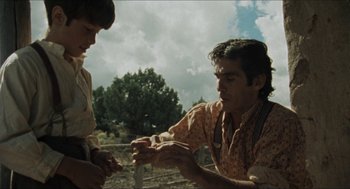 Movie still from “The Ballad of Gregorio Cortez” (1982), directed by Robert M. Young – Two men are sitting on the ground in a field; Medium shot, Over the shoulder angle