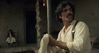 Movie still from “The Ballad of Gregorio Cortez” (1982), directed by Robert M. Young – A man holding a white towel while sitting on a chair; Medium shot, Low angle