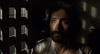 Movie still from “The Ballad of Gregorio Cortez” (1982), directed by Robert M. Young – A man with long hair and a beard looking out a window; Close Up shot, Low angle