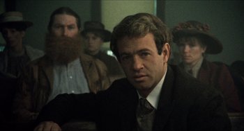 Movie still from “The Ballad of Gregorio Cortez” (1982), directed by Robert M. Young – A man in a suit and tie in front of a group of men; Close Up shot, Over the shoulder angle