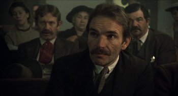 Movie still from “The Ballad of Gregorio Cortez” (1982), directed by Robert M. Young – A group of people in a room with a man wearing a suit; Close Up shot, Low angle