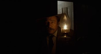 Movie still from “The Ballad of Gregorio Cortez” (1982), directed by Robert M. Young – A man in a suit and tie next to an oil lamp; Close Up shot, Low angle