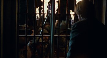 Movie still from “The Ballad of Gregorio Cortez” (1982), directed by Robert M. Young – A person sitting in front of a cage; Medium shot, Over the shoulder angle