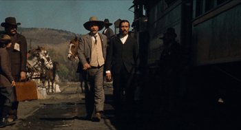 Movie still from “The Ballad of Gregorio Cortez” (1982), directed by Robert M. Young – Two men are walking down the street with a horse; Wide shot, Low angle