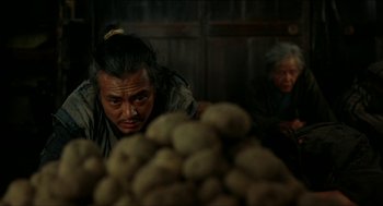 A man sitting in front of a pile of potatoes