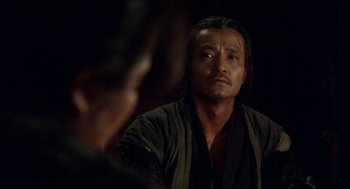 A man with long black hair looking at a mirror