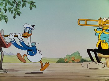 Movie still from “The Band Concert” (1935), directed by Wilfred Jackson – A cartoon of donald duck running in front of a trombone player; Wide shot, Low angle