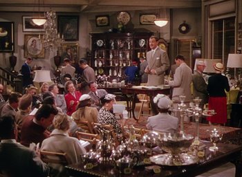 Movie still from “The Band Wagon” (1953), directed by Vincente Minnelli – A group of people sitting around a table; Wide shot, High angle
