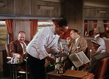 Movie still from “The Band Wagon” (1953), directed by Vincente Minnelli – A man serving drinks to a group of people; Medium shot, High angle