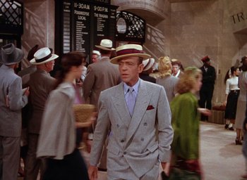 Movie still from “The Band Wagon” (1953), directed by Vincente Minnelli – A man in a suit and hat walking down a street; Medium shot, Over the shoulder angle