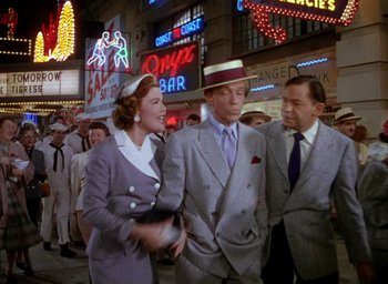 Movie still from “The Band Wagon” (1953), directed by Vincente Minnelli – A group of men and women standing on a city street; Medium shot, Over the shoulder angle