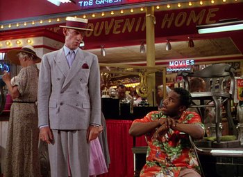 Movie still from “The Band Wagon” (1953), directed by Vincente Minnelli – A man in a suit standing next to a woman in a floral dress; Wide shot, Over the shoulder angle