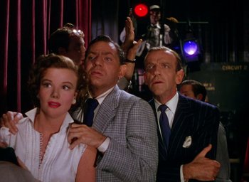 Movie still from “The Band Wagon” (1953), directed by Vincente Minnelli – A group of people standing next to each other in a room; Medium shot, Low angle