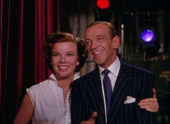Movie still from “The Band Wagon” (1953), directed by Vincente Minnelli – An older man and woman posing for a picture; Medium shot, Low angle