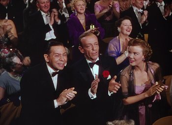 Movie still from “The Band Wagon” (1953), directed by Vincente Minnelli – A group of men and women in formal wear clapping; Medium shot, High angle