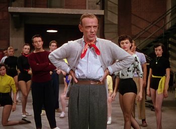 Movie still from “The Band Wagon” (1953), directed by Vincente Minnelli – A group of people standing in a room; Medium shot, Over the shoulder angle