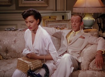 Movie still from “The Band Wagon” (1953), directed by Vincente Minnelli – A man and a woman sitting on a couch together; Medium shot, High angle