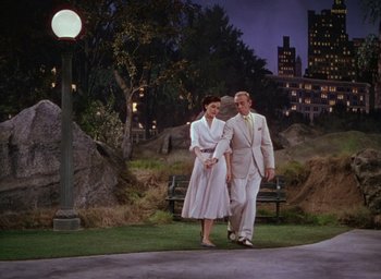 Movie still from “The Band Wagon” (1953), directed by Vincente Minnelli – A man and a woman are walking on the grass; Wide shot, High angle