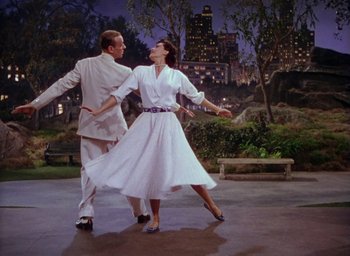 Movie still from “The Band Wagon” (1953), directed by Vincente Minnelli – A man and a woman dancing in front of a city skyline at night; Wide shot, Low angle