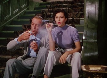 Movie still from “The Band Wagon” (1953), directed by Vincente Minnelli – A man and a woman sitting on steps smoking cigarettes; Medium shot, Low angle
