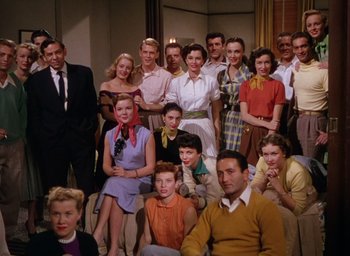 Movie still from “The Band Wagon” (1953), directed by Vincente Minnelli – A group of people posing for a picture in a room; Wide shot, High angle