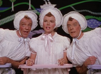 Movie still from “The Band Wagon” (1953), directed by Vincente Minnelli – A group of three people wearing white hats and dresses; Medium shot, Low angle