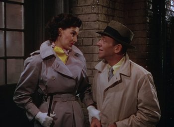 Movie still from “The Band Wagon” (1953), directed by Vincente Minnelli – A man and a woman wearing trench coats and hats; Medium shot, Low angle